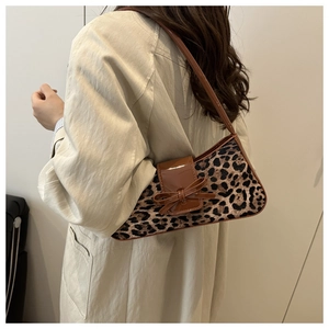 Nahaufnahme der Leopard-Schultertasche mit brauner Lackschleife und beigem Trenchcoat