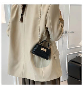 Detail of black croc-embossed mini bag with gold twist lock and fine chain strap