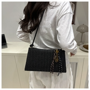 Close-up of woven shoulder bag featuring a unique golden tennis racket charm detail