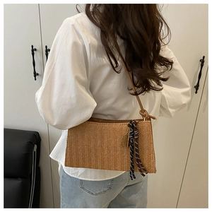 Detail of woven straw tote bag with leather strap and tassel on white shirt model