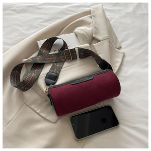 Detail of burgundy suede barrel bag with bohemian geometric strap and metal buckle