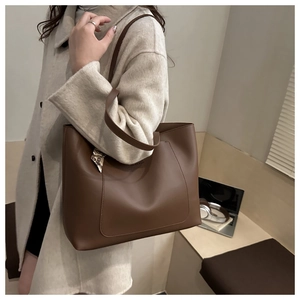 Close-up of a brown matte leather tote bag with silk scarf on shoulder in office setting