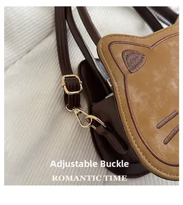 Detail of adjustable gold buckle and brown faux leather material on cat-shaped crossbody bag