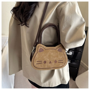 Close-up of a cute cat-shaped crossbody bag with embroidered face and brown top handles