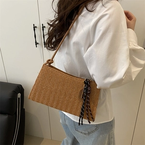 Brown woven shoulder bag with tennis racket charm in a stylish minimalist setting