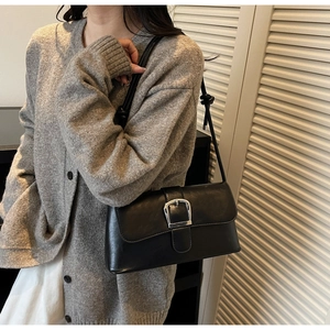 Detail of black faux leather underarm bag with silver buckle and knot strap detail