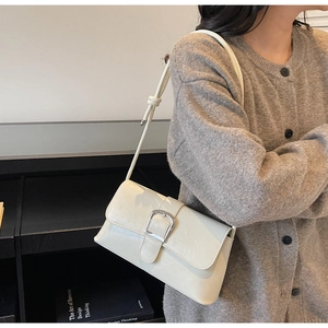 Detail of off-white leather shoulder bag with large silver square buckle and slim strap