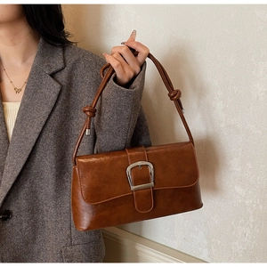 Detail of caramel brown leather shoulder bag with silver square buckle and knotted strap