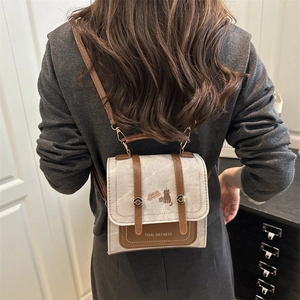 Retro two-tone leather backpack with cat print and metal buckles in a modern interior setting