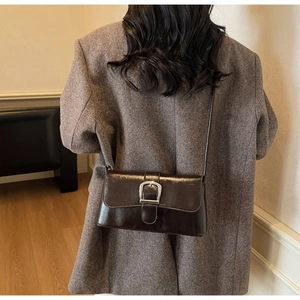 Macro detail of dark brown vintage faux leather crossbody bag with silver buckle accent