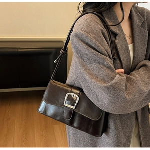 Close-up of retro brown oil-wax leather shoulder bag with a large silver square buckle
