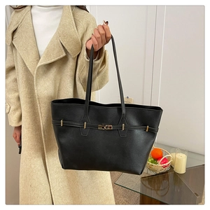 Detail of black tote bag with gold twist lock and minimalist faux leather texture