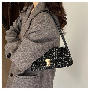 Gros plan d'un sac à bandoulière en tweed noir et doré avec boucle en métal sur un mannequin