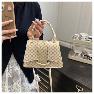 Detail van een crème crossbodytas met bruin monogrampatroon en gouden hardware