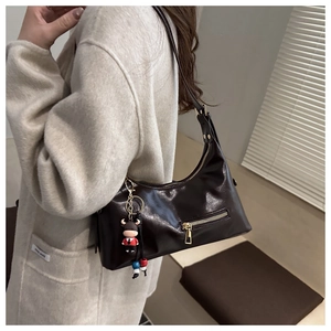 Detail of glossy dark brown leather shoulder bag with a cute calf charm accessory