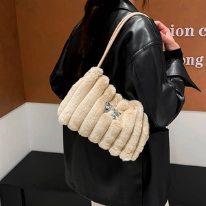 Elegante beige Plüsch-Schultertasche mit silberner Schleife am Modell mit schwarzer Jacke