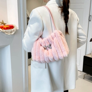 Schicke rosa Kunstfell-Schultertasche mit silberner Metallschleife am weißen Blazer