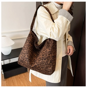 Side view of oversized leopard print tote bag worn over the shoulder in cozy home setting