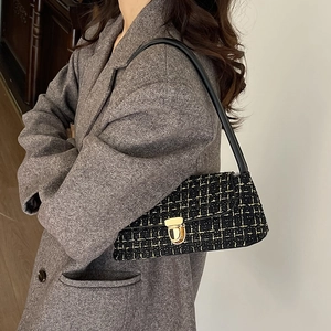 Sac baguette élégant en tweed noir avec boucle dorée porté avec un blazer