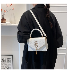 Détail du sac à bandoulière blanc motif croco avec boucle en S dorée sur un mannequin