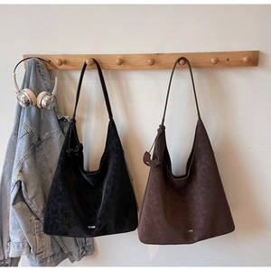 Detail of large hobo tote bags in black and coffee suede with metallic brand logo