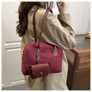 Detail view of burgundy suede tote bag and matching mini pouch on a female model