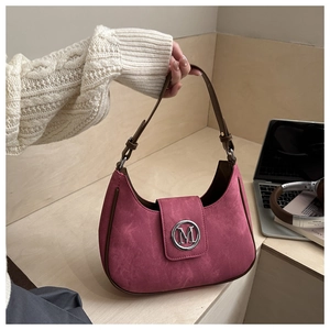 Détail du sac hobo en daim rose avec breloque logo M argentée et bandoulière en cuir brun