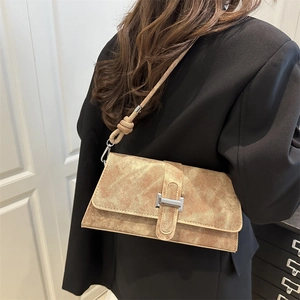 Minimalist light brown textured shoulder bag with silver metal buckle on black suit jacket