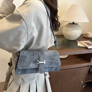 Minimalist grey-blue crossbody bag with silver buckle and knot detail worn by a model