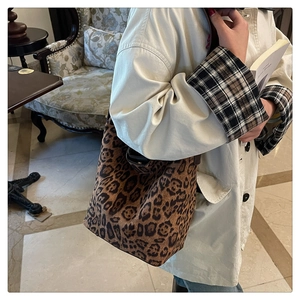 Close-up of leopard print shoulder bucket bag styled with a beige classic trench coat