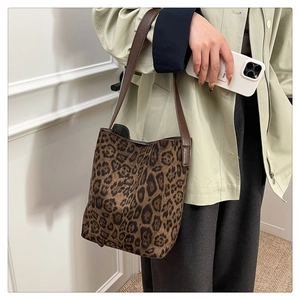Detail of leopard print bucket bag with brown strap styled on a green trench coat