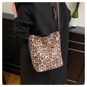 Detailed view of leopard print shoulder bag with brown leather strap on model