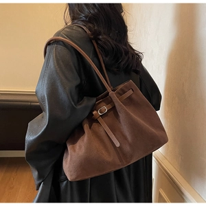 Detail of a brown suede tote bag with a silver buckle and adjustable side straps