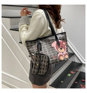 Detail of grey tote bag with bear print and small matching pouch shown on a model