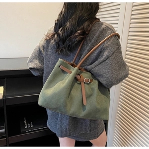 Detail of dark green suede tote bag with brown leather handles and buckle decoration