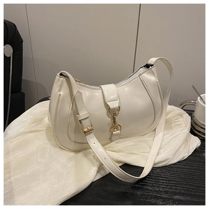 Gros plan du sac besace blanc montrant le cuir brillant et la boucle dorée en métal