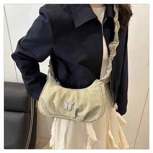Detail of light green pleated bag with silver butterfly buckle and ruffled shoulder strap