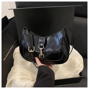 Détail du sac demi-lune en cuir verni noir avec boucle dorée et finition miroir
