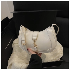 Détail du sac selle blanc en croissant avec fermoir doré posé sur satin en coffret