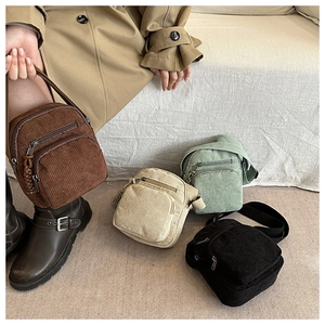 Gros plan du sac bandoulière en velours côtelé avec double zip et texture tissu