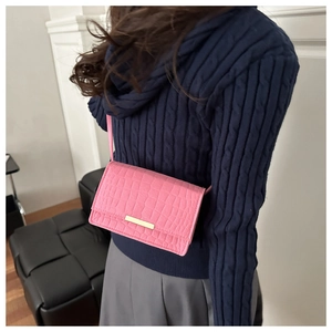 Détail du sac rose motif crocodile avec fermoir doré et fine bandoulière réglable