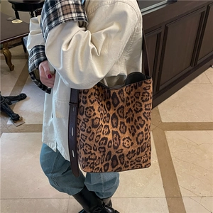 Fashionable leopard print bucket bag with brown leather strap in a retro indoor setting