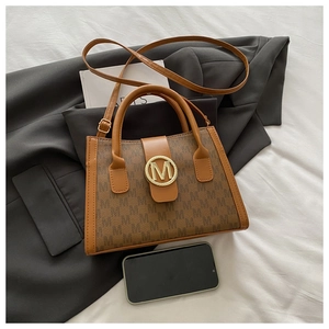 Macro detail of brown monogram Boston bag featuring vintage gold M-shaped metal lock closure