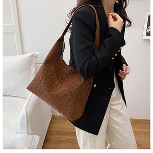 Detail of a large leopard print hobo bag showing texture and drape on a model's shoulder