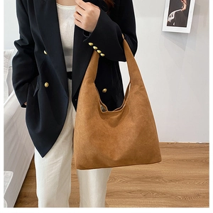 Detail of a large brown suede shoulder bag in a minimalist hobo style for daily commuting