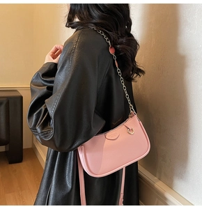 Détails d'un sac bandoulière en cuir rose texturé avec chaîne et lanière en cuir