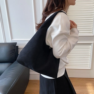 Minimalist black oversized tote bag for women worn on shoulder for a casual winter look
