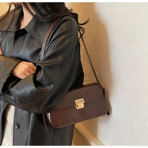Détail d'un sac à bandoulière en cuir marron foncé avec un fermoir en métal doré carré