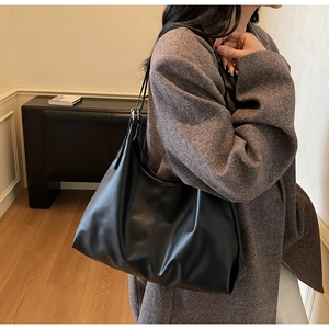 Macro shot of large black matte leather tote bag showing soft texture and shoulder drape
