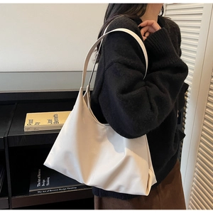 Side view of a minimalist cream leather shoulder bag with smooth texture and sleek design